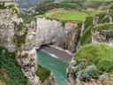 Kalksteinfelsen und Bucht mit grünem Wasser in einer Küstenlandschaft.