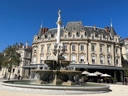 Brunnen vor historischem Gebäude mit blauen Himmel.