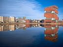 Moderne Gebäude spiegeln sich in einem ruhigen Gewässer.