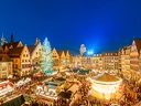 Weihnachtsmarkt auf einem Platz mit beleuchteten Fachwerkhäusern.