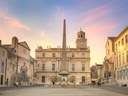 Historischer Platz mit Obelisk und alten Gebäuden bei Sonnenuntergang.