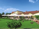 Aussenbereich eines Restaurants mit Terrasse und Garten im Sonnenschein.