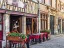 Gepflasterte Strasse mit Tischen vor einem Restaurant.