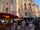 Menschen auf einem Markt vor einer alten Kirche.