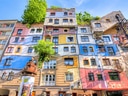 Bunt bemaltes Gebäude mit Bäumen auf dem Dach, klare Himmel.
