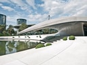 Moderne Architektur mit gewölbtem Gebäude und Teich im Freien.