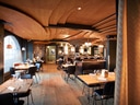 Modernes Restaurant mit Holzdecke und stilvoller Einrichtung.