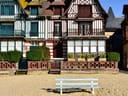 Fachwerkhäuser am Strand mit einer Bank im Vordergrund.