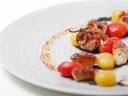 Feines Gericht mit gegrilltem Oktopus, gelben und roten Tomaten auf Teller.