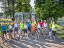 Gruppe von Radfahrern mit Fahrrädern auf einem Weg am Fluss.