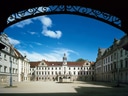 Innenhof eines majestätischen Schlosses unter blauem Himmel.