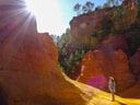 Person wandert durch bunte Felslandschaft bei Sonnenschein.