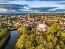 Luftaufnahme einer Stadt mit Fluss, Bäumen und historischen Gebäuden.