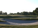 Golfplatz mit grünen Rasenflächen und Sandbunkern.