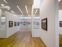 Moderner Galerieraum mit Gemälden an weissen Wänden.