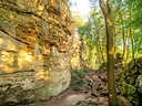 Wanderweg durch bewaldeten Felsenpfad bei Sonnenlicht.