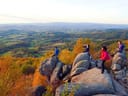 Menschen auf Felsen vor herbstlicher Landschaft.