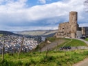 Burg auf Hügel mit Flussblick und Stadt im Tal.