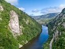 Steingesicht am Fluss zwischen bewaldeten Bergen.