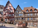 Fachwerkhäuser am Marktplatz mit Brunnen in einer Altstadt.