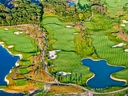 Luftaufnahme eines Golfplatzes mit Seen und Bäumen.