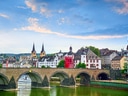 Steinbrücke über den Fluss in einer historischen Stadt mit Kirchtürmen.