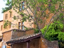 Historische Steinmauer mit blühendem Baum davor.