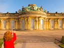Person fotografiert Schloss Sanssouci im Sonnenschein.