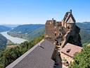 Burg auf einer Anhöhe mit Blick auf Fluss und Landschaft.