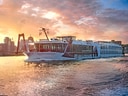 Flusskreuzfahrtschiff bei Sonnenuntergang auf dem Wasser.