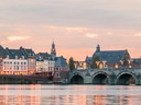 Altstadt und Steinbrücke über einen Fluss bei Sonnenuntergang.