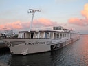 Langes Flusskreuzfahrtschiff am Ufer bei Sonnenuntergang.