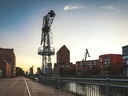 Industriekran und Gebäude an der Hafenkante bei Sonnenuntergang.