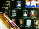 Nahaufnahme eines aufgeschlagenen Buches vor einem genealogischen Wanddiagramm.
