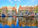 Farbenfrohe Häuser am Amsterdamer Kanal mit Booten.