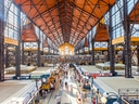 Grosse, belebte Markthalle mit hohen Decken und Ständen.