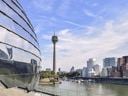Stadtlandschaft mit Fluss, modernen Gebäuden und einem Fernsehturm.