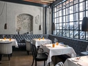 Elegantes Restaurant mit gedeckten Tischen und grossen Fenstern.