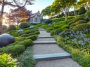 Gepflegter Gartenweg mit Häuschen im Hintergrund.
