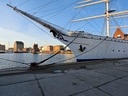 Segelschiff im Hafen mit Stadt im Hintergrund.