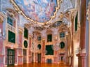Prunkvoller Saal mit bemalter Decke und kunstvoll dekorierten Wänden.
