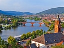 Panoramablick auf Fluss, Brücke und Stadt in grüner Landschaft.