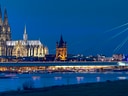 Beleuchtete Brücke und Kirche bei Nacht mit Fluss im Vordergrund.