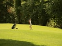 Person spielt Golf auf grünem Golfplatz.