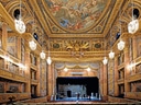 Prunkvolles Theater mit bemalter Decke und Kronleuchtern.