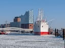 Schiff im Hafen vor modernem Gebäude mit blauem Himmel.
