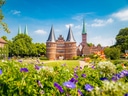 Holstentor in Lübeck mit blühenden Blumen im Vordergrund.