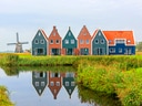 Reihenhäuser und Windmühle am Kanal in grüner Landschaft.