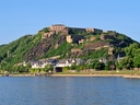 Festung auf grünem Hügel am Flussufer.