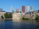 Historische Gebäude am See mit modernen Hochhäusern im Hintergrund.